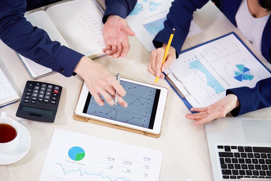 A team of business people using a tablet, with a calculator and documents spread out for their work.